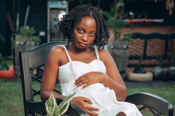 photo of a pregnant woman wearing a white dress sitting in a garden