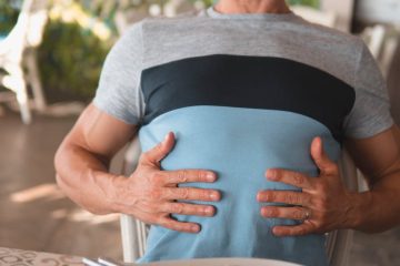 man with hands on his abdomen suffering after eating too much