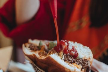 crop woman eating hamburger in cafe