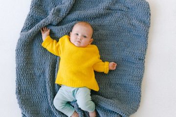 adorable newborn baby resting on soft blue plaid in studio