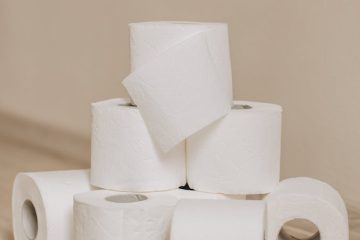 tubes of white toilet paper on bathroom floor