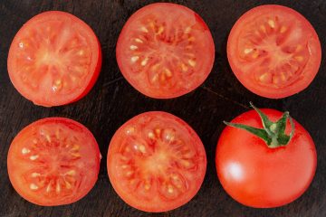 fresh sliced and whole tomatoes on cutting board