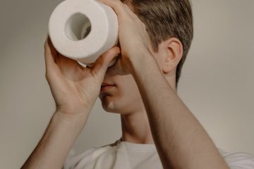 man in white crew neck t shirt holding white tissue roll