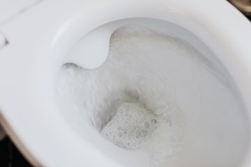 flushing water in white toilet bowl