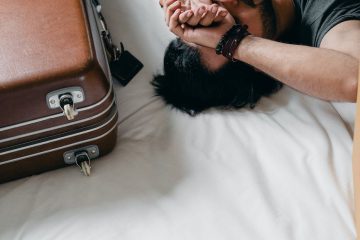 tired ethnic man lying on bed during relocation in new house