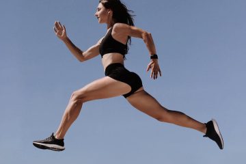 woman in black sports bra and black shorts jumping on air under blue sky