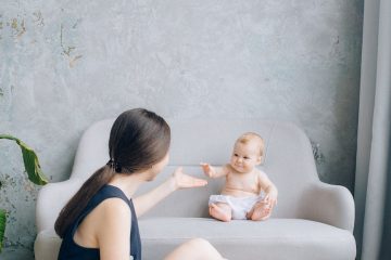 baby sitting on a sofa chair and a woman sitting on the floor