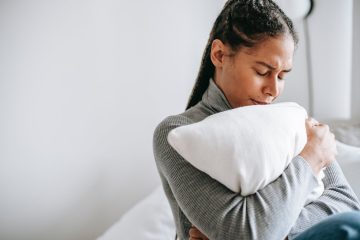 ethnic sad woman embracing pillow in solitude