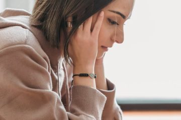 sad woman with hands on head in room