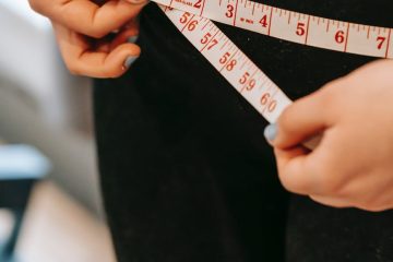 plus size woman measuring hips in gym