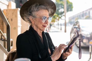 woman in black dress looking at her smartphone