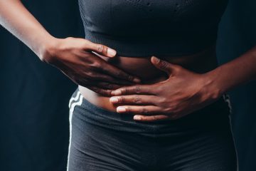 person wearing black active wear holding her tummy
