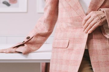 woman in pink and white plaid blazer sitting on brown wooden chair