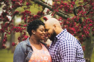 pregnant black woman caressing husband near tree