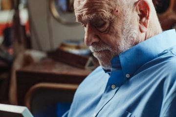 an elderly man in blue shirt looking at the picture frame