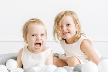 two children playing in a pool with balls